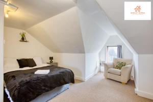 ein Schlafzimmer mit einem Bett und einem Stuhl im Dachgeschoss in der Unterkunft Bridgwater Bliss: 6-Bedroom Haven for Large Groups in Bridgwater