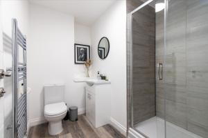 a bathroom with a toilet and a glass shower at 6-Bedroom Apartments at the Heart of Nottingham in Nottingham