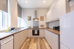 a kitchen with white cabinets and a wooden floor at 6-Bedroom Apartments at the Heart of Nottingham in Nottingham