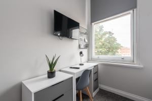 Dieses weiße Zimmer verfügt über einen Schreibtisch und ein Fenster. in der Unterkunft 6-Bedroom Apartments at the Heart of Nottingham in Nottingham
