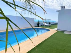 una piscina en medio de un patio con césped en Costa Teguise 3 bed villa with sea view on the golf estate, en Teguise