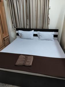 Ce lit se trouve dans un dortoir doté d'un matelas et d'oreillers blancs. dans l'établissement A & P Apartments, à Thane
