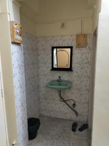 La salle de bains est pourvue d'un lavabo vert et d'un miroir. dans l'établissement A & P Apartments, à Thane