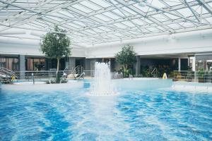 a large pool with a fountain in a building at V Spa & Conference Hotel in Tartu