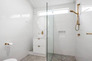 a white bathroom with a shower and a sink at Super House, Super Host in Kalgoorlie +3 photos