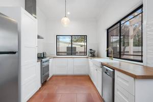 a kitchen with white cabinets and a large window at Super House, Super Host in Kalgoorlie