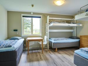 Habitación con 2 camas, mesa y escritorio. en Sudersand Resort en Fårö