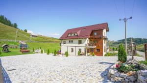 een huis met een rood dak aan een stenen weg bij Casa Bălan in Fundăţica