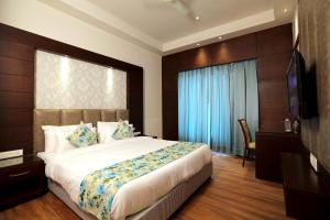 um quarto com uma cama grande e uma televisão em The Stella Hotel & Resort em Ludhiana