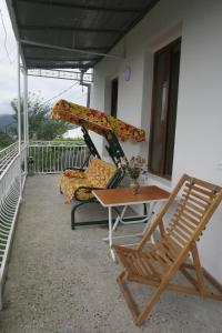 Un balcón con 2 sillas, una mesa y un columpio en Guest House Nona, en Kutaisi