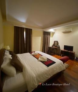 ein Schlafzimmer mit einem großen weißen Bett in einem Zimmer in der Unterkunft Le Luxe Boutique Hotel in Ban Nongdouang