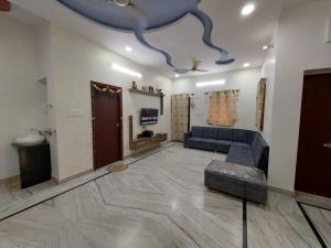 a living room with a blue couch and a tv at Entire Villa in Jodhpur