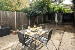 a table and chairs in a backyard with a fence at Pleasant 4 bed house with x6 beds in heart of Croydon !! - Photo ID Required in Croydon