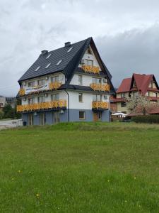 a large white building with a black roof at Apartament Zielona Przystań Kluszkowce - 1 km od VELO CZORSZTYN I CZORSZTYNSKI!!! in Kluszkowce