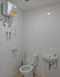 La salle de bains blanche est pourvue de toilettes et d'un lavabo. dans l'établissement Yuvin rooms by Vivo Apartment, à Seturan
