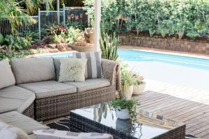 a patio with a couch next to a swimming pool at Studio 26: Central, Hampton’s Poolside Hideaway in Coffs Harbour