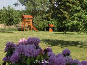 un parque con parque infantil y flores púrpuras en Ferienwohnungen am Federower Hofsee, en Federow