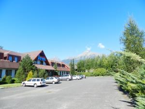 a parking lot with cars parked in front of a mountain at Hotel Autis in Vysoké Tatry
