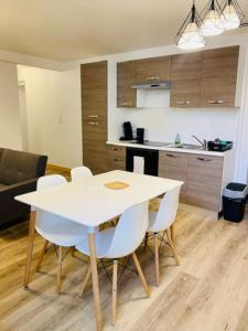 a kitchen with a white table and white chairs at L'Escapade à Coligny in Coligny +8 photos