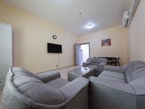 a living room with two couches and a flat screen tv at Hor Al Anz Star Residence - Home Stay in Dubai