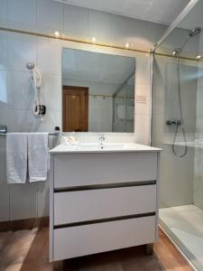 een badkamer met een witte wastafel en een douche bij Aparthotel El Serch in Andorra la Vella