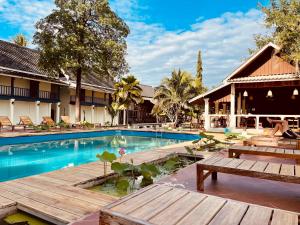 a pool at a resort with benches and tables at The Jam Hostel Luang Prabang in Luang Prabang