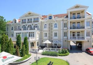 un grand bâtiment blanc avec une voiture garée devant. dans l'établissement Hotel Aurum, à Hajdúszoboszló