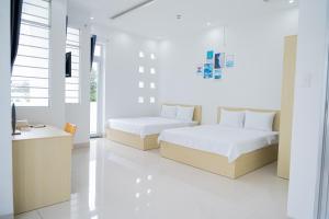 a bedroom with two beds and a desk in it at An Gia Hotel Tây Ninh in Tây Ninh