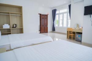 a bedroom with two beds and a desk with a computer at An Gia Hotel Tây Ninh in Tây Ninh