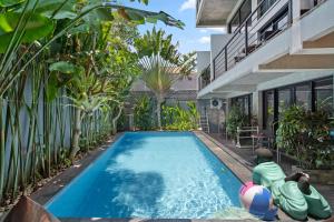 two people in a swimming pool in a house at Balissimo Apartment by Hombali in Seminyak