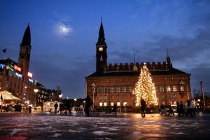 a christmas tree in front of a building with a clock tower at City Center Apartments 739 in Copenhagen