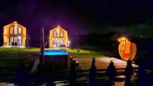 una casa con una piscina delante de ella por la noche en Domki Diabolina - sauna, jacuzzi, klimatyzacja, kominki en Krajno Pierwsze