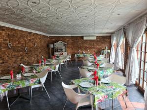 un comedor con mesas y sillas y una pared de ladrillo en Royal Villa Guesthouse en Brakpan