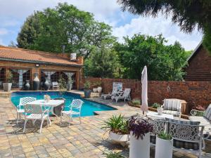 un patio con mesa, sillas y piscina en Royal Villa Guesthouse en Brakpan