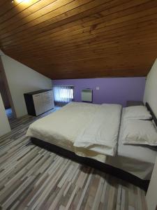 a bedroom with a large bed with a wooden ceiling at Апартамент Родопи in Smolyan