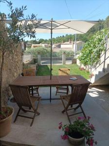 沙托阿爾努聖奧邦的住宿－La petite Jarlandine，庭院里配有一张带椅子和遮阳伞的木桌