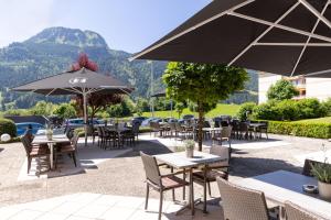 eine Terrasse mit Tischen, Stühlen und einem Sonnenschirm in der Unterkunft DIE GAMS Hotel Restaurant in Bad Hindelang