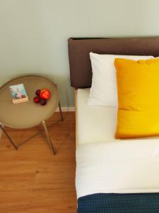 ein Bett mit einem gelben Kissen und einem Tisch mit Obst in der Unterkunft Luvono Apartments - 2 Schlafzimmer / Netflix / Disney+ in Magdeburg