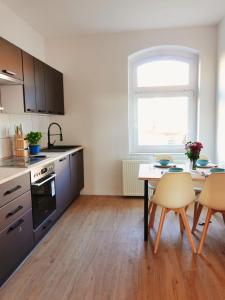 eine Küche mit einem Tisch und Stühlen sowie einem Tisch und einem Fenster in der Unterkunft Luvono Apartments - 2 Schlafzimmer / Netflix / Disney+ in Magdeburg