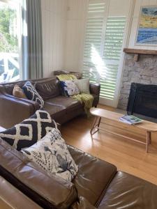 ein Wohnzimmer mit einem Ledersofa und einem Kamin in der Unterkunft Apollo Bay Oceanview Mountain Retreat, Pet Friendly, EV station, Fireplace in Apollo Bay