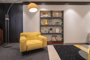 a yellow chair in a room with a book shelf at Nouvelle Hotel Seoul Itaewon in Seoul