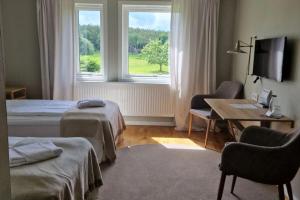 a bedroom with two beds and a desk and a window at Bommersvik Hotell & Konferens in Järna +40 photos
