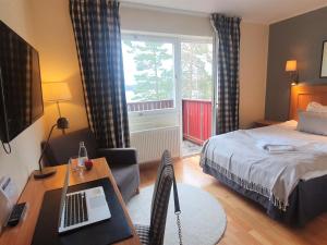 a hotel room with a bed and a desk with a laptop at Bommersvik Hotell & Konferens in Järna