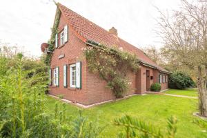 uma casa de tijolos vermelhos com um jardim verde em Familienhaus am Meer em Dornum