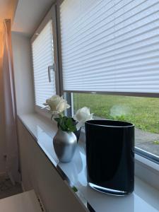 a vase on a counter with flowers in a window at SIR WALTER Work & Stay, HOMEOFFICE, W-LAN in Neuss