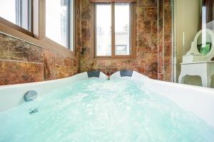 加平的住宿－Die Pause Pool villa Pension，浴室设有装满蓝色水的浴缸。