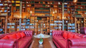 a library with two red leather couches and books at Avalon Ubud Castle & SPA in Ubud