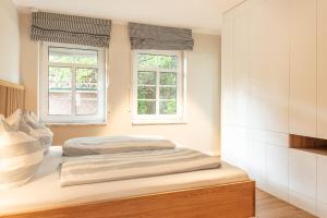 a bed in a room with two windows at Familienhaus am Meer in Dornum