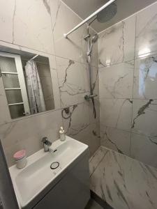 a white bathroom with a sink and a shower at Aux Terrasses de la Lune in Paris