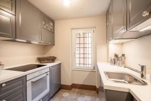 a kitchen with gray cabinets and a sink and a window at Casa Gelsomina in Gardone Riviera +41 photos